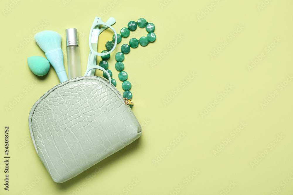 Cosmetic bag with accessories on green background Stock Photo | Adobe Stock