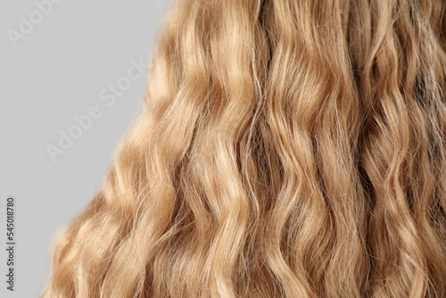 Closeup view of curly blonde hair on light background