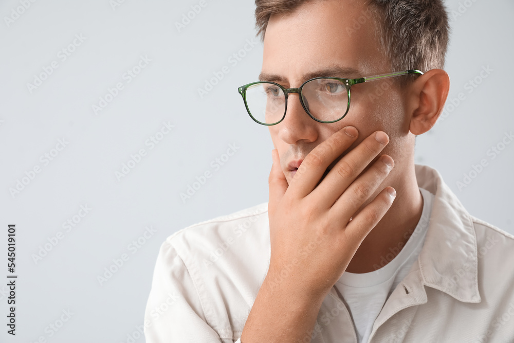 Stressed young man with eyeglasses on light background, closeup Stressed young man with eyeglasses on light background, closeup