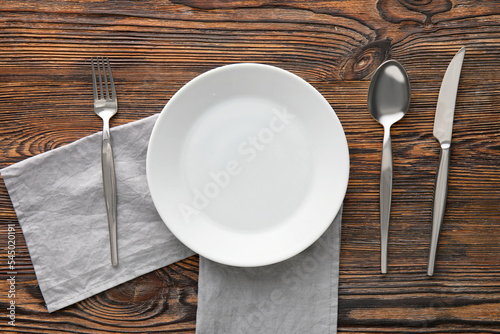 Table setting with plate  napkin and cutlery on wooden background