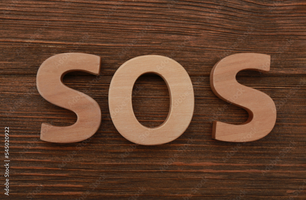 Abbreviation SOS made of letters on wooden table, top view Abbreviation SOS made of letters on wooden table, top view