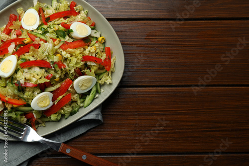 Delicious salad with Chinese cabbage and quail eggs served on wooden table, top view. Space for text