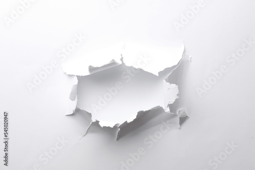 Hole in white paper on light background