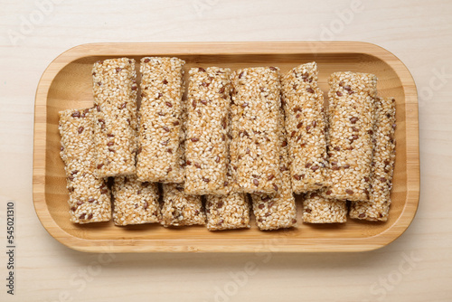 Plate with tasty sesame seed bars on wooden table, top view. Space for text