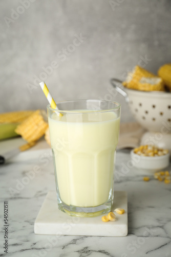 Tasty fresh corn milk in glass on white marble table