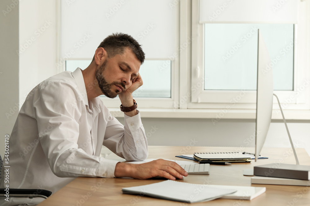 Naklejka premium Sleepy man snoozing at workplace in office