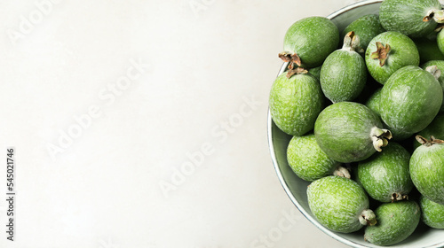 Fresh green feijoa fruits in bowl on light grey table, top view with space for text. Banner design