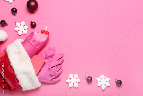 Fototapeta Naklejka Na Ścianę i Meble -  Santa hat with cleaning supplies and Christmas decor on pink background