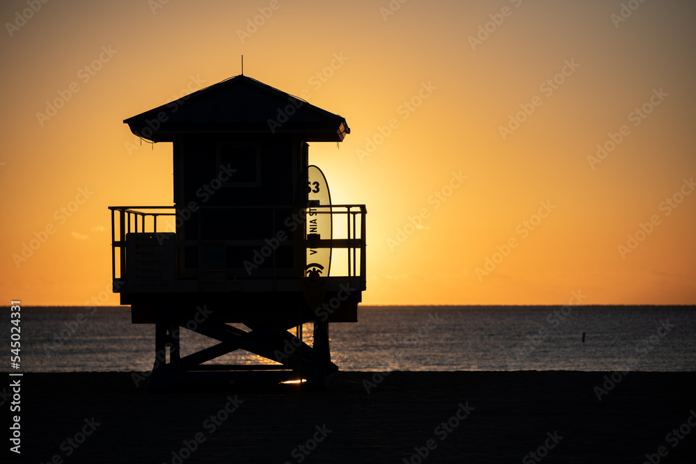 Life Guard tower is silhouetted against a colorful sunrise on Hollywood Beach, Florida