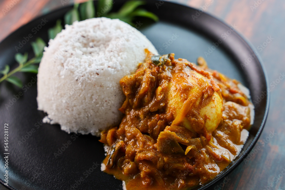 Egg roast curry or Mutta roast gravy hot and spicy dish popular spicy Kerala food with puttu appam on wooden background Tamil Nadu South India. Egg roast curry or Mutta roast gravy hot and spicy dish popular spicy Kerala food with puttu appam on wooden background Tamil Nadu South India.