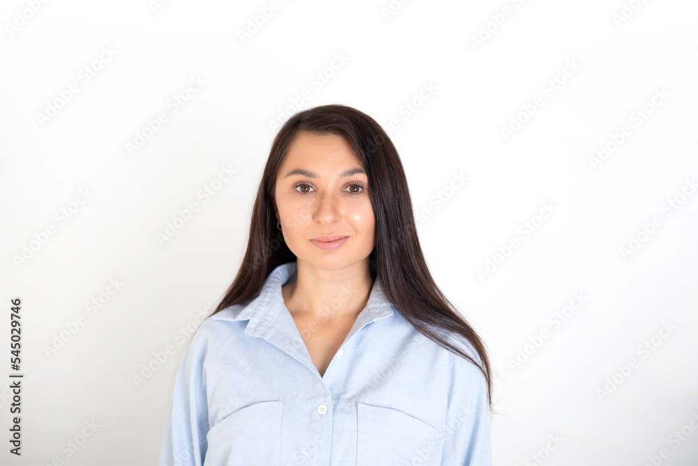 Portrait of a beautiful brunette woman in a blue shirt on a white background. Neutral makeup. Space for text Portrait of a beautiful brunette woman in a blue shirt on a white background. Neutral makeup. Space for text