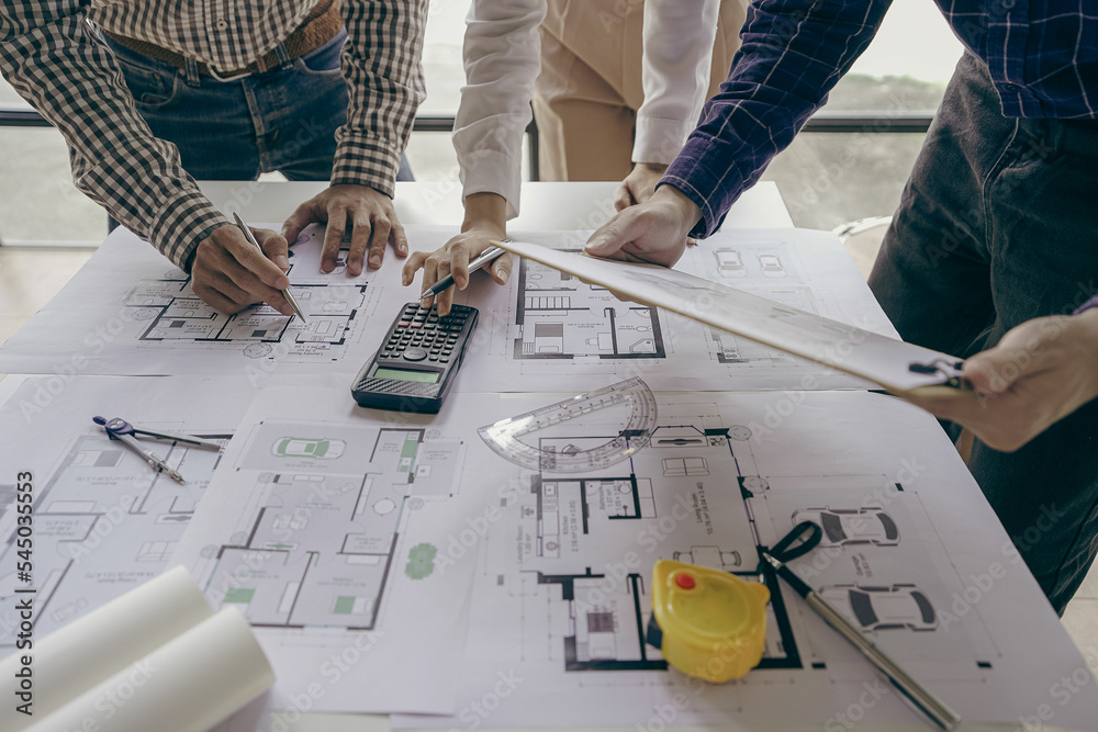 © ArLawKa - Architects and engineers point to buildings on blueprints and use laptops to draw house project designs in a construction concept office. © ArLawKa - Architects and engineers point to buildings on blueprints and use laptops to draw house project designs in a construction concept office.