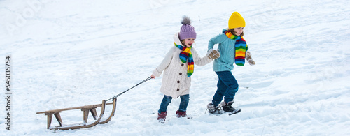Winter children with sled. Active winter outdoors games. Happy kids friends on winter vacation.