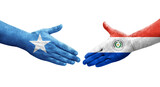 Handshake between Paraguay and Somalia flags painted on hands, isolated transparent image.