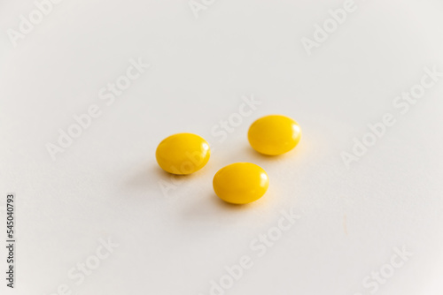 白いテーブルの上に三粒の黄色の錠剤