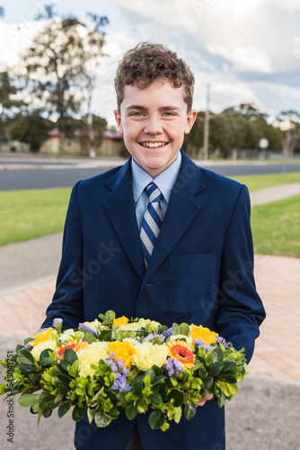 Boy wearing school uniform holding wreath for remembrance service