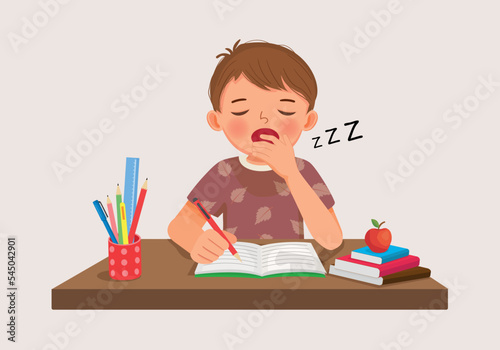 cute little boy yawning feeling sleepy while studying doing homework on the desk