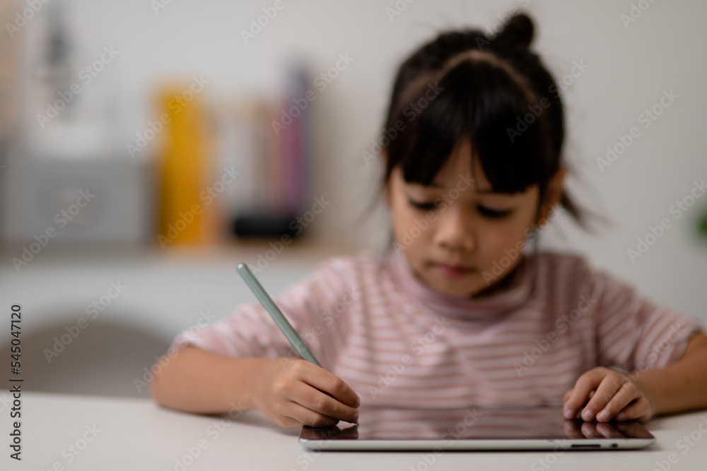 Asian little cute girl touching the digital tablet screen on the table Asian little cute girl touching the digital tablet screen on the table