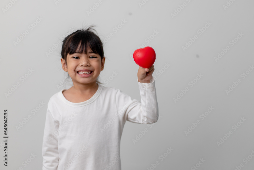 Portrait of Asian little girl child holding red heart sign on white background Portrait of Asian little girl child holding red heart sign on white background
