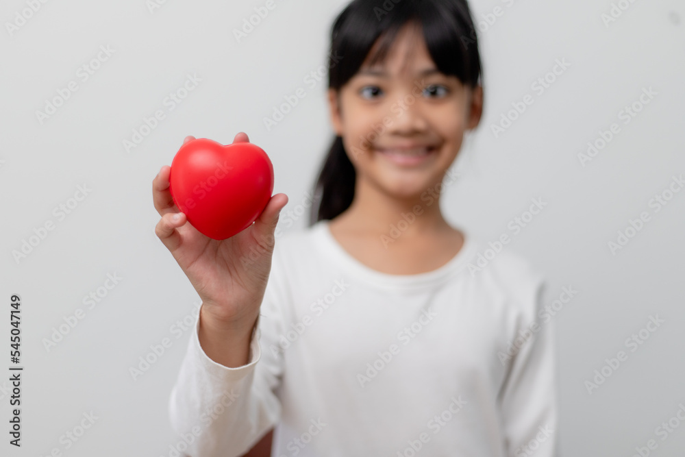 Portrait of Asian little girl child holding red heart sign on white background Portrait of Asian little girl child holding red heart sign on white background