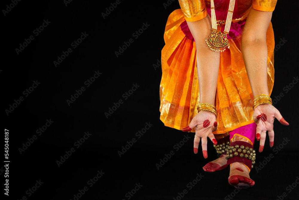 Female Indian classical dancer performing Bharatanatyam dance poses in dark background with copy space. 