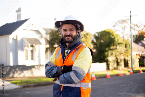 Smiling road worker man with beard wearing high vis jacket with his arms crossed photo