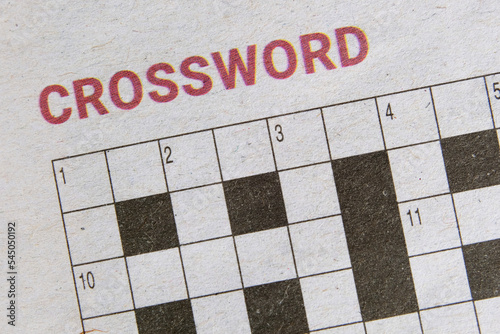Crossword puzzle in a local newspaper for readers to challenge themselves mentally by solving cryptic word clues. A crossword puzzle in the papers with name or title printed at the top. Closeup view. photo