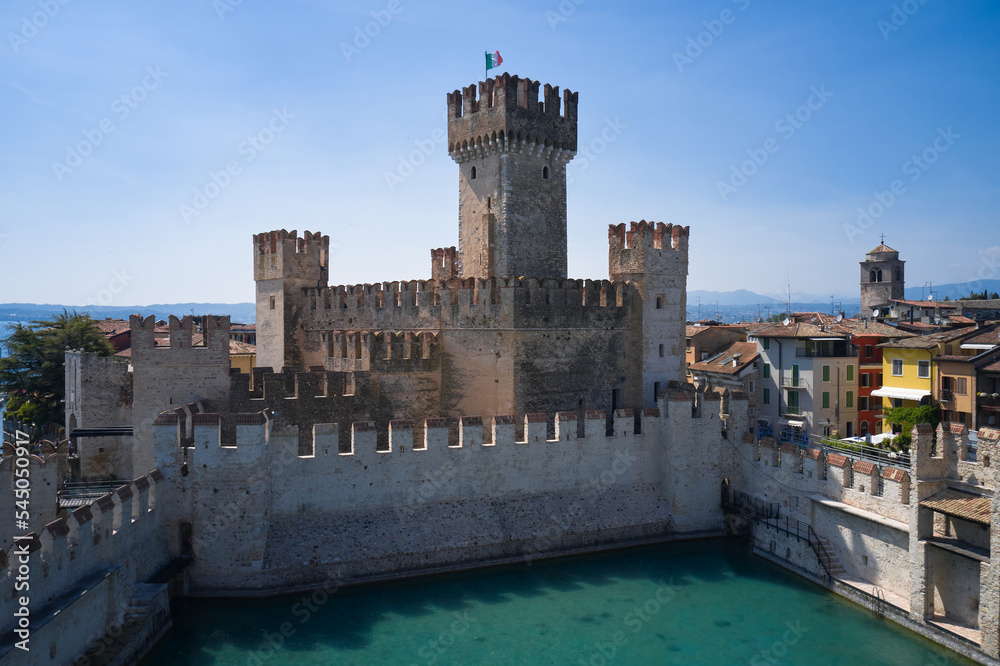 Italian flag on the main tower of Scaligero Castle Sirmione, Lake Garda. Aerial view of Sirmione, Lake Garda. Lago di Garda, Lombardy region of Italy drone view.