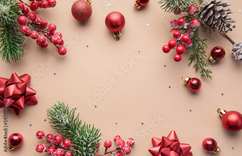 Bright Christmas frame of spruce, red christmas decorations on beige background.