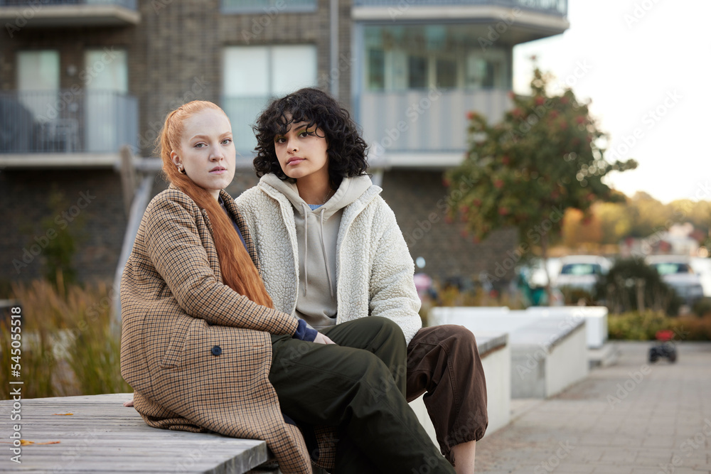 Portrait of young female friends sitting outdoors Portrait of young female friends sitting outdoors