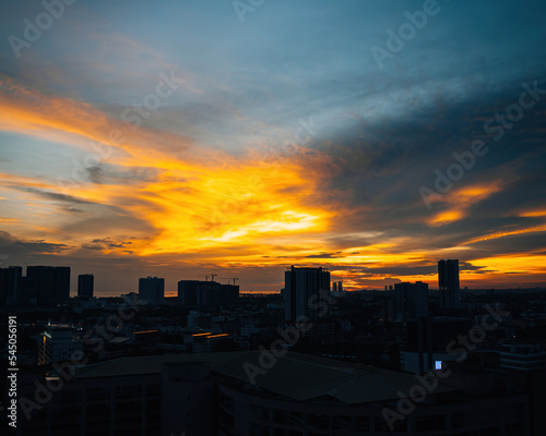 Horizon at sunset with golden blue sky with some clouds. City silhouette.