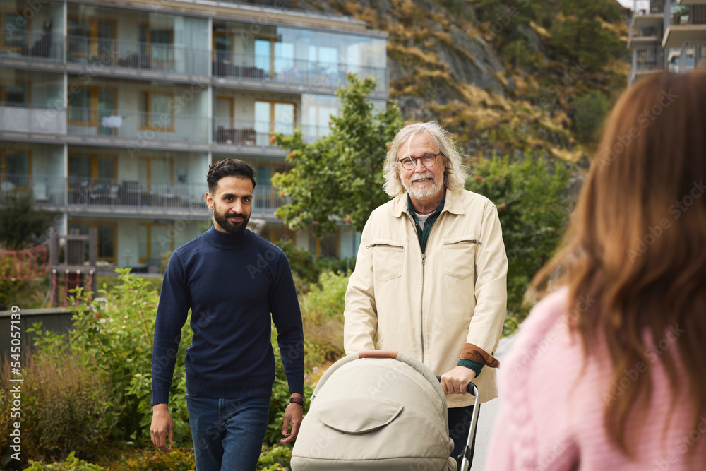 Men with baby stroller walking in residential area