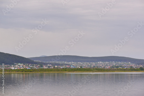 view of a beautiful city by the lake surrounded by low mountains © Elena