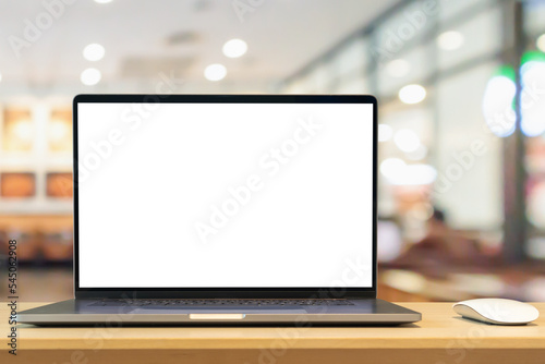 Laptop with blank screen on wood table with cafe coffee shop blur background