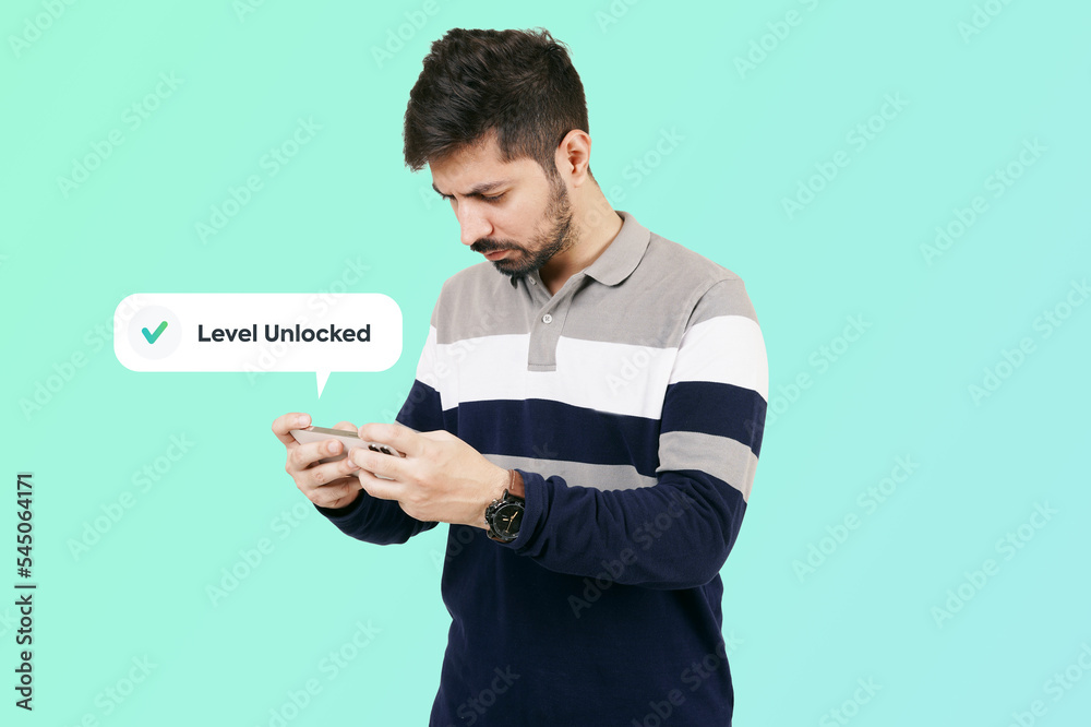 man using a mobile phone. Mobile Gaming. Young male playing online game on mobile phone. Smartphone gaming. A focused young guy playing game on a mobile phone to unlock new level man using a mobile phone. Mobile Gaming. Young male playing online game on mobile phone. Smartphone gaming. A focused young guy playing game on a mobile phone to unlock new level
