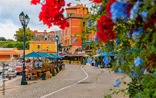 Seaside promenade with flowers and traditional houses along Mediterranean Sea in Villefranche sur Mer Old Town on the French Riviera, South of France photo