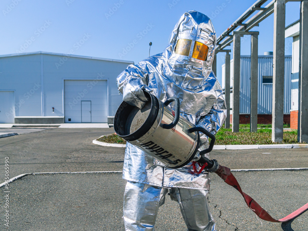 Naklejka premium Elimination of accidents and fires at petrochemical industry facilities. Fireman's protective suit to protect against high temperature in case of fire. Emergency situation at the oil storage facility.