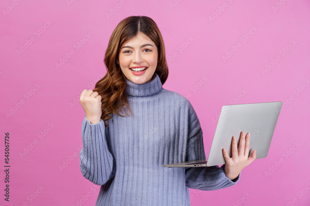 Portrait of Happy successful young woman holding laptop in her hands while standing isolated over pink background. Technology and Business concept. Portrait of Happy successful young woman holding laptop in her hands while standing isolated over pink background. Technology and Business concept.