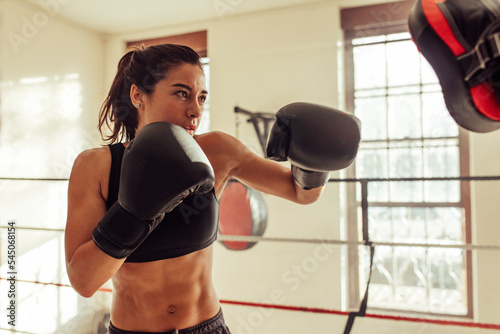 Female boxer punching focus pads in a boxing ring © Jacob Lund