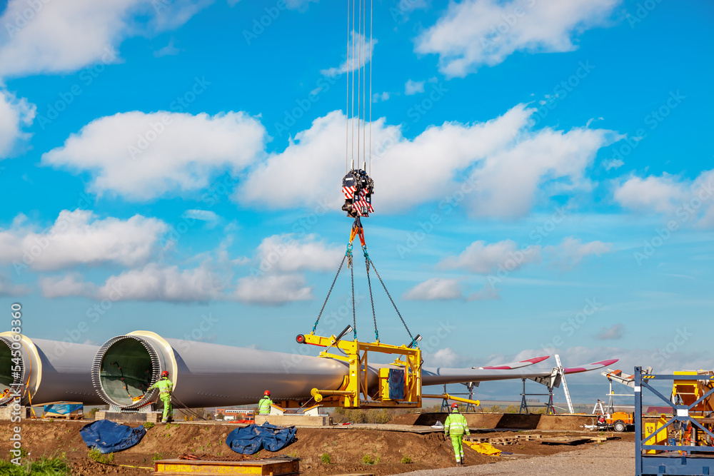 Fototapeta premium Construction work by crane. one blade laying on the ground. Building and assembling a windturbine. Green energy, ecology, CO2-footprint reduction concept. Wörrstadt 