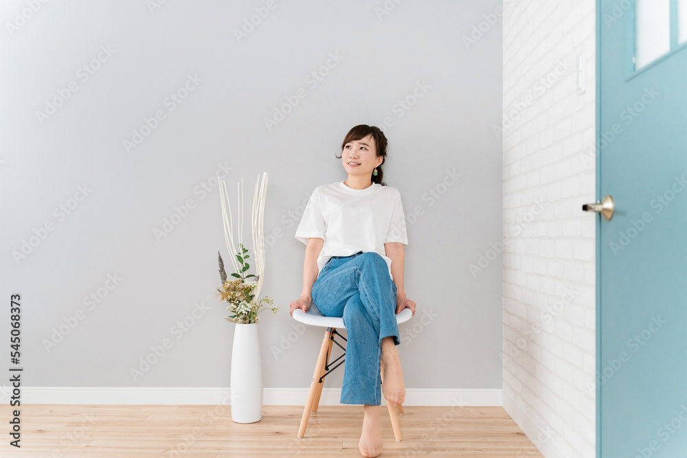 家で椅子に足を組んで座るジーンズ姿のアジア人女性 Stock Photo | Adobe Stock