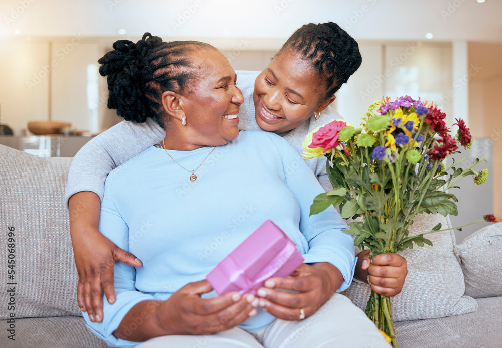 Black woman, mothers day and hug with flowers on sofa for love, box or gift to mom in home. Woman, bouquet and senior mama with wow, smile or happy for surprise, celebration or birthday on couch - obrazy, fototapety, plakaty 