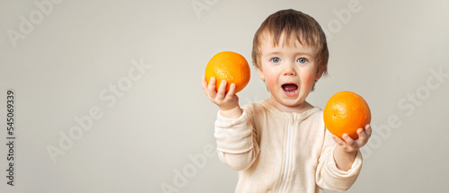 a baby with a food allergy holds oranges in his hands, the child has red cheeks, irritation