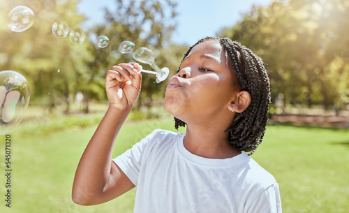 Valokuva Park, child and black girl blowing bubbles enjoying fun time alone outdoors, joy and childhood development