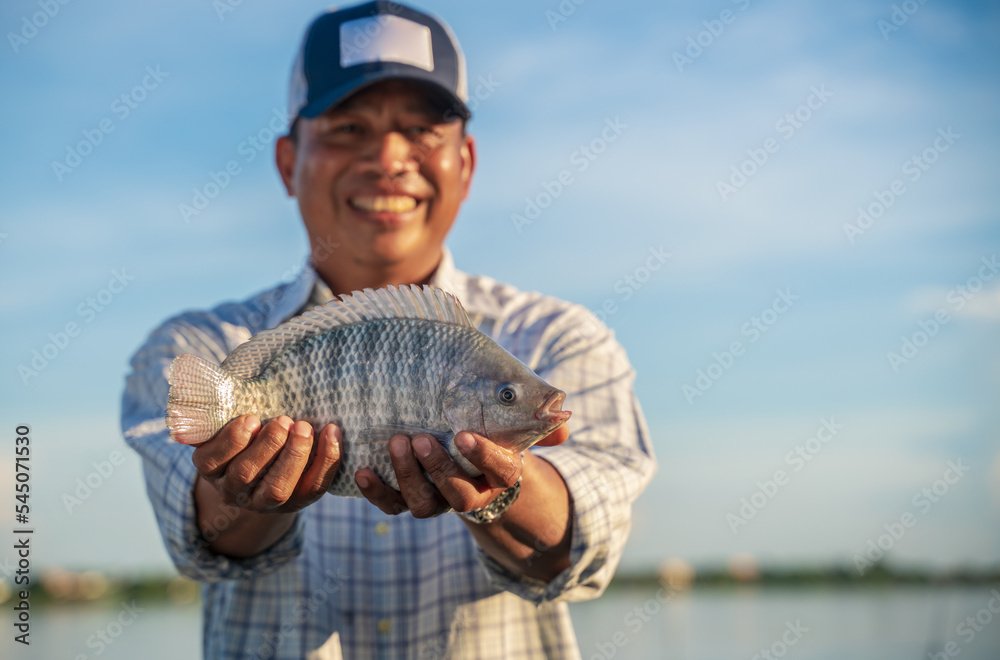 Aquaculture farmer man showcasing quality-raised tilapia in his hands Aquaculture farmer man showcasing quality-raised tilapia in his hands