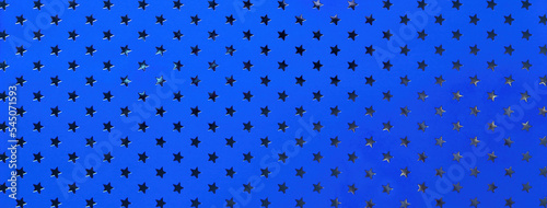 Navy blue background from metal foil paper with a pattern of silver sparkling stars. Sapphire decorative wrapping backdrop