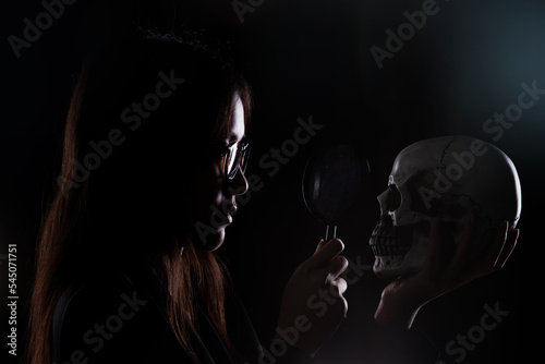 Detective Collecting looking Evidence cause of dead in a Crime Scene. White Bone Skull found under Sand. Magnifier investigate some clue mystery, copy space. Dark silhouette