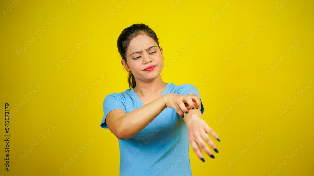 Young women have skin problems, irritation on her skin, skin infection itching red rash, arm scratching with hands, isolated over yellow background