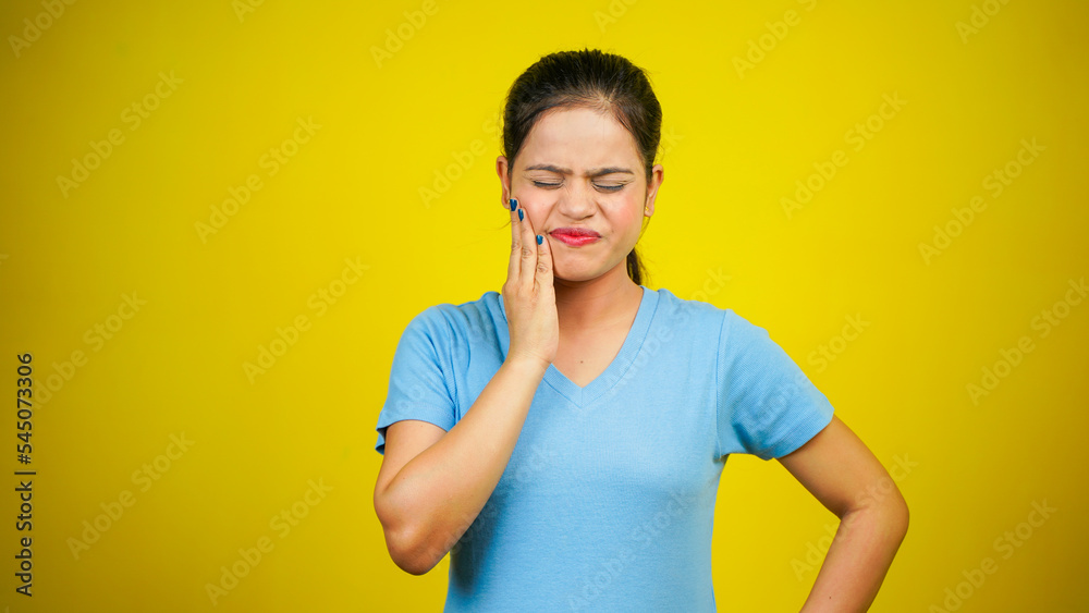 Young woman scratching face or cheek, isolated over yellow background. Annoying itching and