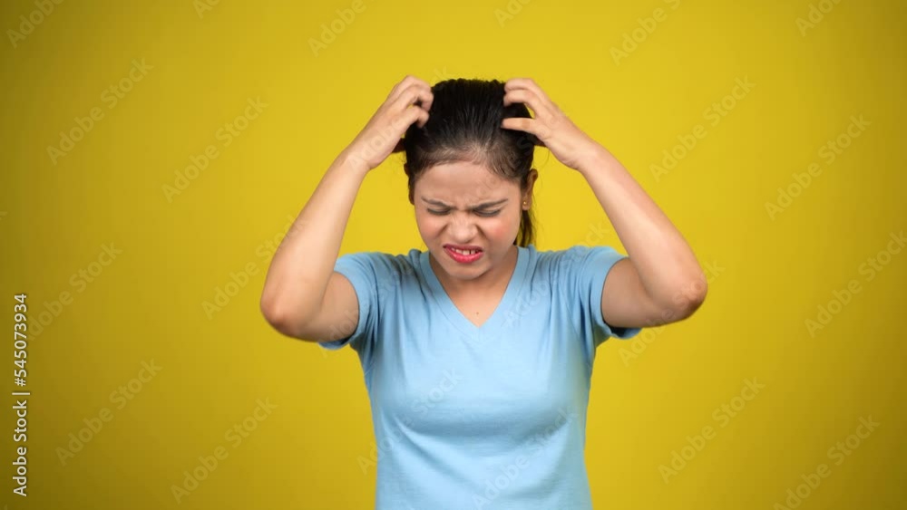 Young nervous woman scratches her head, hair itching on yellow background Young nervous woman scratches her head, hair itching on yellow background